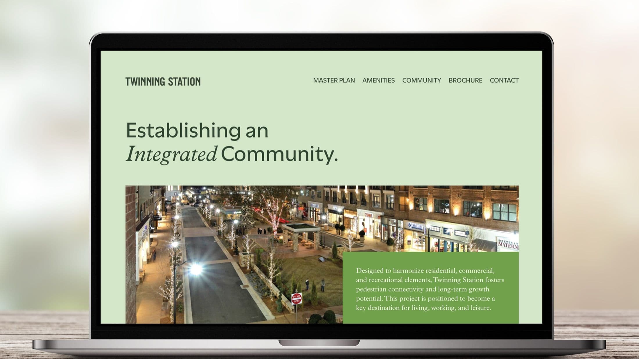 Twinning Station website mockup on a laptop showing the master plan navigation, a nighttime street view, and a paragraph describing the project as a key destination for living, working, and leisure.