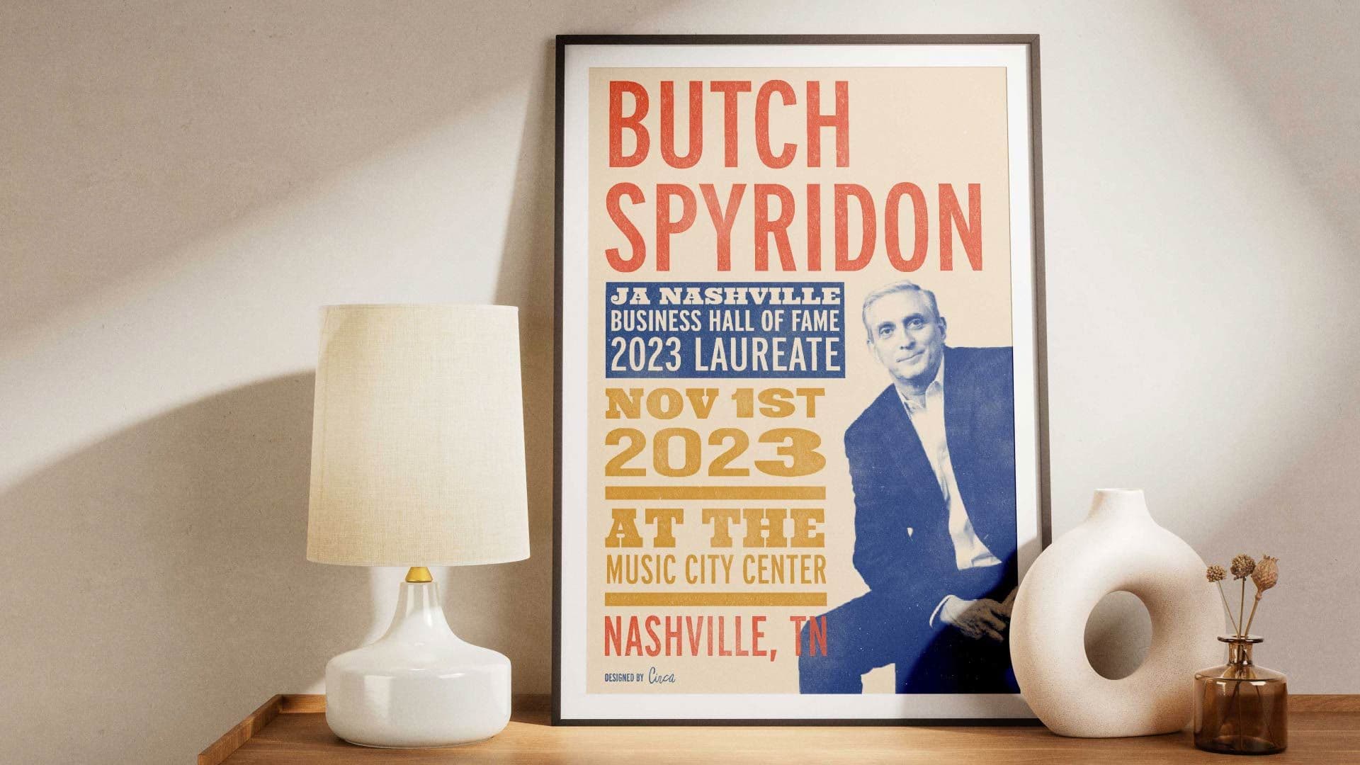 Butch Spyridon poster in a frame next to a lamp