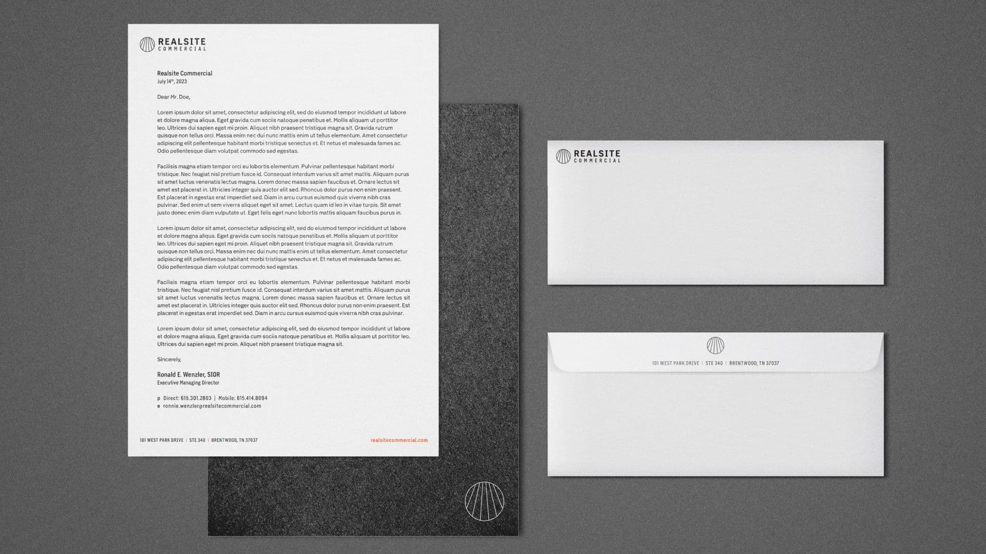 A top-down shot of a corporate branding mock-up shows a letterhead and two envelopes on a dark gray surface. The stationery features the "REALSITE COMMERCIAL" logo and contact information, presenting a professional and unified look for the brand.